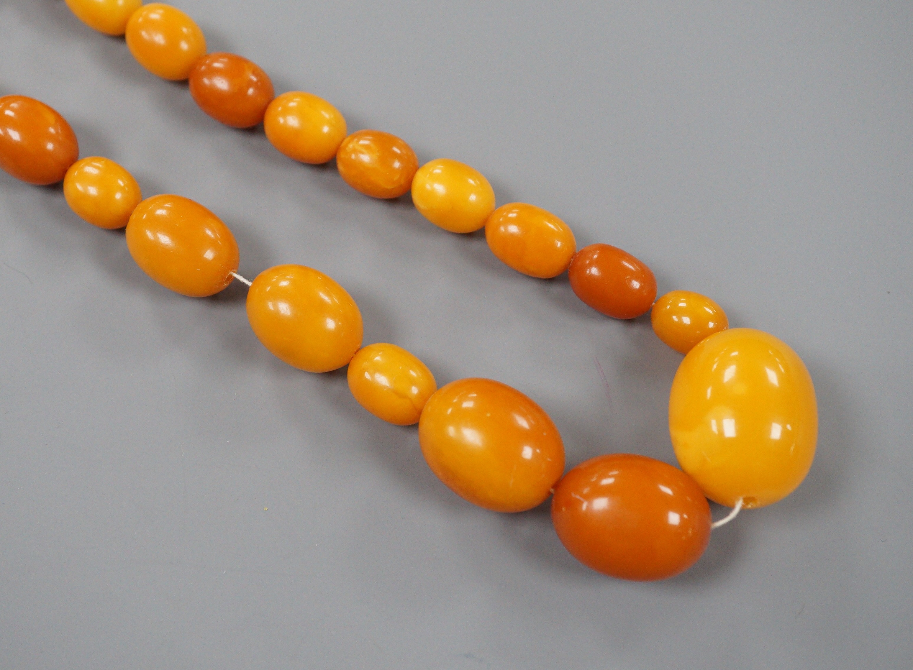 A single strand graduated oval amber bead necklace, 96cm, gross weight 106 grams.